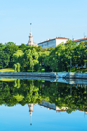 The river banks are covered with green grass and green trees in cloudy weatherの写真素材