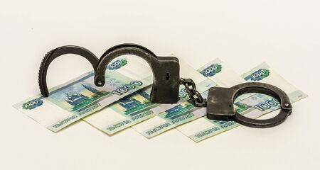 On a white background are banknotes 1000 Russian rubles. kupyurazh lie on black metal handcuffs.の写真素材