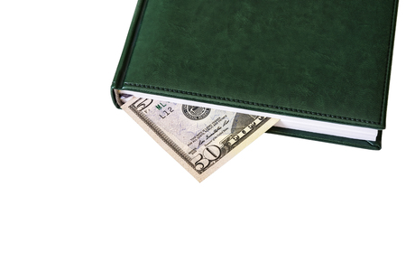 Between the sheets of the closed diary is visible part of the money billの写真素材
