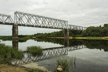 Over the river bed on the concrete supports there is a railway bridgeの写真素材