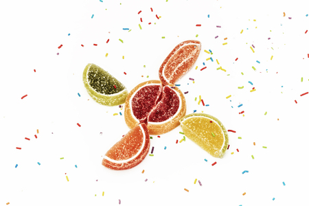 On a white background scattered confectionery powder and lie citrus fruit wedges of marmaladeの写真素材