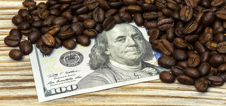 On a wooden background is a money bill and coffee beansの写真素材