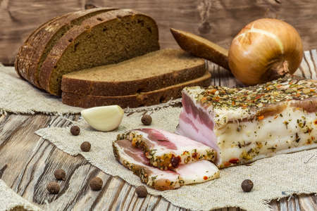 Rustic still life. Rustic salted bacon with bread, onion and garlicの写真素材
