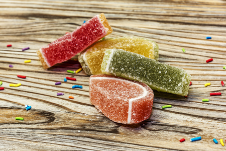 Lobules of colorful marmalade lie on a wooden surface