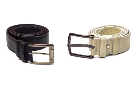 White and black leather belts twisted and lying on a white backgroundの写真素材