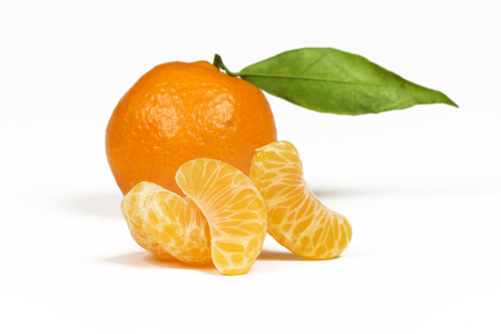 On a white background three slices of mandarin close-up on a foreground and whole orange mandarin in the backgroundの写真素材