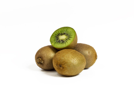 On a white background there are three whole kiwis and one cut kiwi lies on topの写真素材