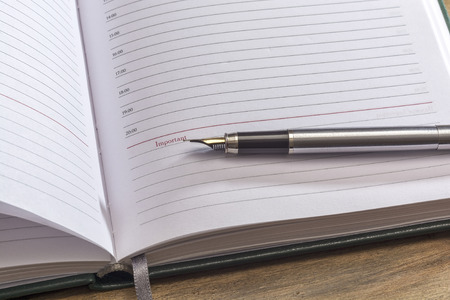 On the page of the open diary is a fountain pen, close-up, wooden surfaceの写真素材