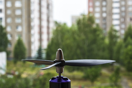 A close-up of a propeller with three blades on an electric motor of a quadcopter, a blurred...