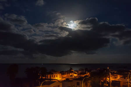 Night landscape. The light of the moon over the sea and the city nightlife. Stock photographyの写真素材