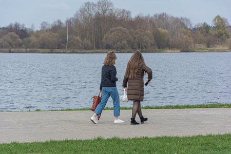 Two girls are walking along the embankment along the river. Stock photography.の写真素材