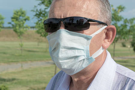 man wearing sunglasses and a medical mask. Close-up, blurry background. Stock Photoの写真素材