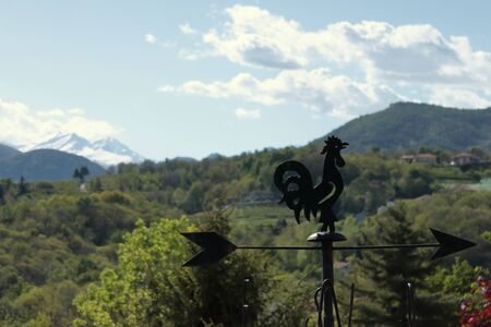 Portrait of a wind cockerel and the last snow-capped mountains on the backgroundannouncing the springの写真素材