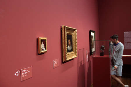 A tourist is looking at three paintings from a Young Gustav Klimt in a Purple wall at Leopold Museum, Wien.のeditorial素材