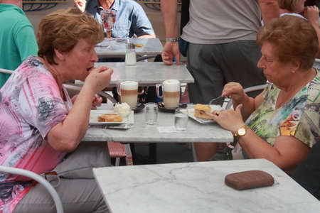 two old ladies are eating a slice of cake and sipping a melange in a cafe in Viennaのeditorial素材