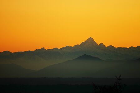 A sunset over a body of water with a mountain in the backgroundの写真素材