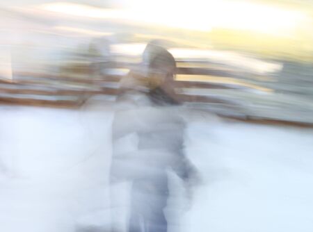 A blurry photo of a blonde girl with a white dress in a snow fieldの写真素材
