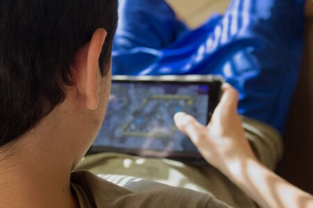 Caucasian boy sitting in an armchair checks his social networks on the tabletの写真素材