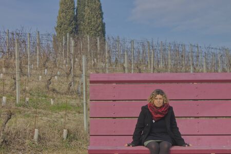 a Caucasian woman sitting on a giant pink benchの写真素材