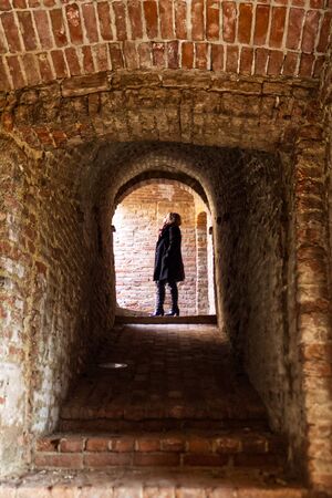 a Caucasian woman looks towards the suns rays from the stairs of a dungeonの写真素材
