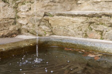 a fountain drips into a stone tank in an Alpine village
