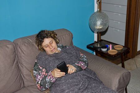 Caucasian woman checks messages on social networks on her mobile phone sitting in an armchair