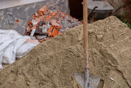 Close-up of a shovel stuck in a pile of sand on a construction siteの写真素材
