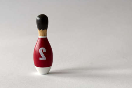 rearview of a wooden puppet in the shape of a bowling pin with a number two shirt