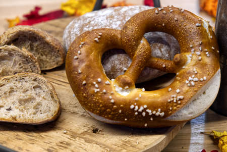 a composition of cereal bread and pretzels on a wooden cutting boardの写真素材