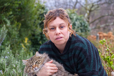 brunette fifty aged caucasian woman with green striped mallet cuddles a cat
