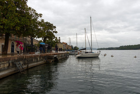 Salo, Garda Lake, Italy - 24 apr 2022: Citizens walking by waterfront in a rainy day.のeditorial素材