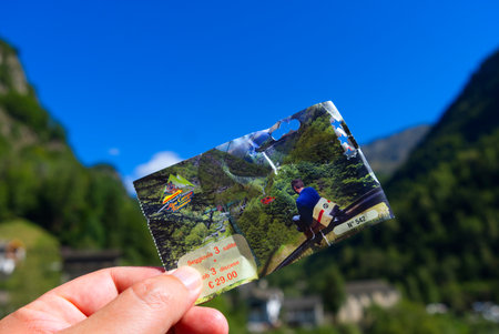 focus on a hand holds the ticket for the summer toboggan above an alpine backdrop