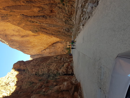 A person is standing on the edge of a road beside a steep cliffの写真素材