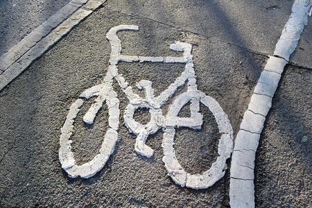 White painted bicycle on a cycling line at pavement