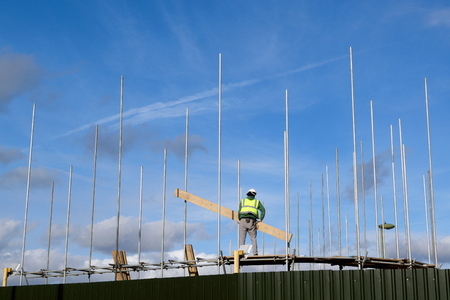 Worker with protective clothes holding wooden board on a construction site