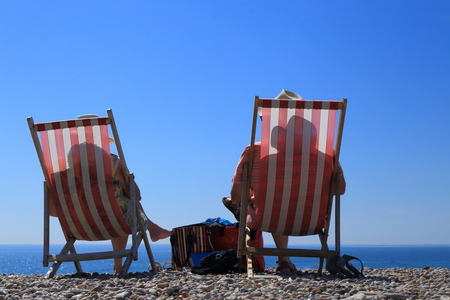 Shadows of people sitting on deck chairs on the beach in Devonの写真素材