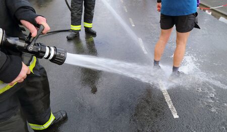Runner washing mud from legs with sprinkler after the race on muddy terrain in Devon, UKの写真素材