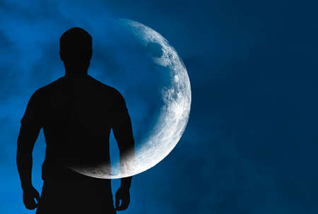 Silhouette of man with transparent crescent or moon on body in front blue sky during night, concept picture about space, astronomy and astrologyの写真素材