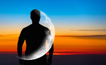 Silhouette of man with transparent crescent or moon on body in front blue sky during sunset, concept picture about space, astronomy and astrologyの写真素材