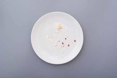 White plate with crumbs and cream after sweet cake, top viewの写真素材