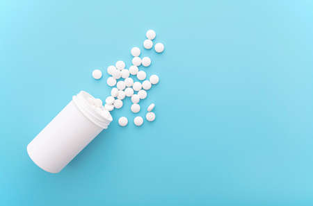 Medical background with white bottle and pills on blue surface, top view, space for text, concept pictureの写真素材