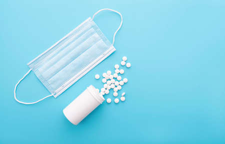 Medical background with white bottle and pills, medical mask, top view, concept pictureの写真素材