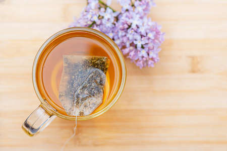 Hot beverage in glass mug on wooden table. Close-up herbal tea in bag tea, top viewの写真素材