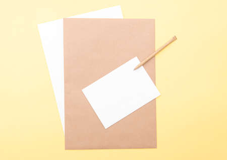 Composition with brown and white blank sheets, pen on yellow background, layout with space for text, top viewの写真素材