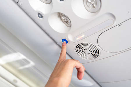 Passenger pressing the button to call cabin crew, stewardess for a service