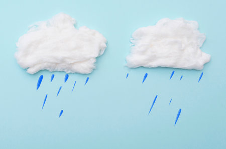 Cumulus clouds by cotton wool with rain drops on blue surface, layout for ideas, space for textの写真素材