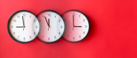 Round wall clocks on red surface showing 9, 12, 3, layout, top view, place for textの写真素材