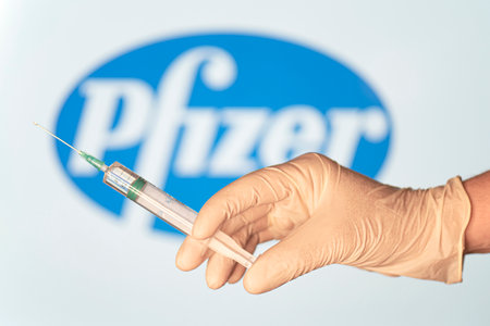 BERLIN - JAN 17: Concept staged picture. Coronavirus vaccine by Pfizer, doctor's hand with syringe and vaccine against Pfizer logotype in Berlin, January 17.2021 in Germanyのeditorial素材