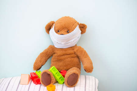 Brown teddy bear toy with protective medical mask at child roomの写真素材