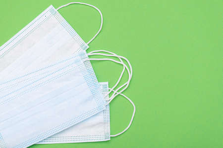 Protective medical masks on green background, top view, medical theme